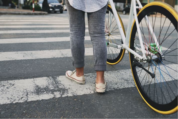 ciclista con bicic en mano cruzando por senda peatonal